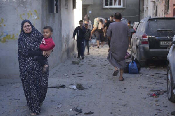 A Palestinian woman carries her child after an Israeli strike in the Nusseirat refugee camp in the Gaza Strip on Saturday, Nov. 4, 2023. (AP Photo/Hatem Moussa)