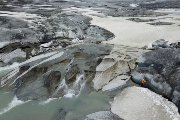 Matthias Huss, of the Federal Institute of Technology in Zurich and glacier monitoring group GLAMOS, drills holes into the Rhone Glacier near Goms, Switzerland, June 10, 2025. (AP Photo/Matthias Schrader)