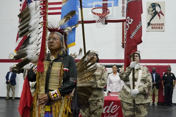 FILE - James Nells, of the Navaho Tribe, and a teacher at Riverside Indian School, leads the Riverside Indian School color guard during opening ceremonies Saturday, July 9, 2022, in Anadarko, Okla., for a meeting to allow U.S. Secretary of the Interior Deb Haaland, rear, to hear about the painful experiences of Native Americans who were sent to government-backed boarding schools designed to strip them of their cultural identities. The list of boarding schools in the U.S. that once sought to “civilize” Native Americans, Alaska Natives and Native Hawaiians is getting longer. The National Native American Boarding School Healing Coalition released a new interactive map Wednesday, Aug. 30, 2023. (AP Photo/Sue Ogrocki, File)