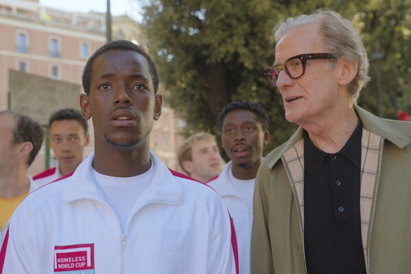 This image released by Netflix shows Micheal Ward, foreground left, and Bill Nighy in a scene from "The Beautiful Game." (Alfredo Falvo/Netflix via AP)
