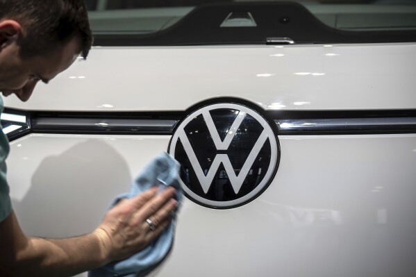 FILE - A VW logo on an I.D. Buzz is polished before Volkswagen AG's annual press conference in Berlin, Germany, Tuesday, March 14, 2023. Volkswagen saw after-tax earnings fall by 20% in the first half of the year to 8.5 billion euros ($9.45 billion) as the automaker tries to engineer a rebound in China. (Michael Kappeler/dpa via AP, File)