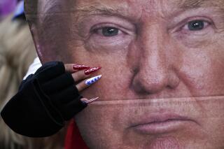 A woman holds a cutout of President Donald Trump's face at a rally in Washington in support of Trump called the "Save America Rally" on Jan. 6, 2021. (AP Photo/Jacquelyn Martin)