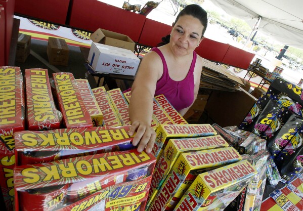 FILE - Dominique Tafoya arranges some of the new fireworks stock at a local fireworks concession stand, July 1, 2011, in Phoenix. Extremely hot, dry conditions forecast through the Fourth of July across much of the West are heightening concerns about wildfires and the dangers of fireworks. (AP Photo/Ross D. Franklin, File)