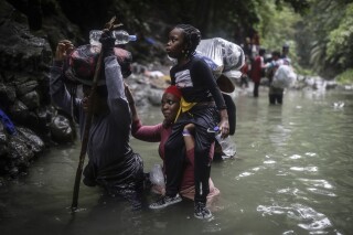 Haitian migrants wade through a river as they cross the Darien Gap from Colombia to Panama in hopes of reaching the United States, May 9, 2023. (AP Photo/Ivan Valencia)