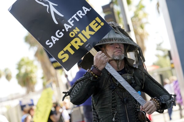 FILE - SAG-AFTRA member Bruce D. Mitchell participates in a post apocalyptic-themed picket line outside Netflix studios, Nov. 8, 2023, in Los Angeles. Hollywood’s actors have voted to ratify the deal with studios that ended their strike after nearly four months, leaders announced Tuesday, Dec. 5, 2023. (AP Photo/Chris Pizzello, File)