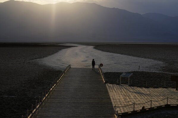 A person walks on a boardwalk at the salt flats at Badwater Basin, Monday, Aug. 17, 2020, in Death Valley National Park, Calif. Death Valley recorded a scorching 130 degrees (54.4 degrees Celsius) Sunday, which if the sensors and other conditions check out, would be the hottest Earth has been in more than 89 years and the third-warmest ever measured. (AP Photo/John Locher)