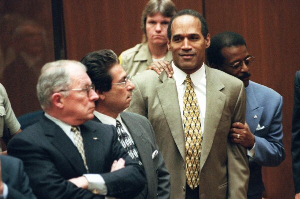 FILE - In this Oct. 3, 1995 file photo, attorney Johnnie Cochran Jr. holds O.J. Simpson as the not guilty verdict is read in a Los Angeles courtroom. At left is F. Lee Bailey and second from left is Robert Kardashian. Casey Anthony tells The Associated Press she sees parallels in her story to O.J. Simpson. The Florida woman was accused of killing her toddler when she went missing. Years earlier, Simpson was acquitted of killing his wife and her friend. Anthony also was acquitted but says both were tried unfairly in the court of public opinion. (AP Photo/Pool, Myung J. Chun, File)