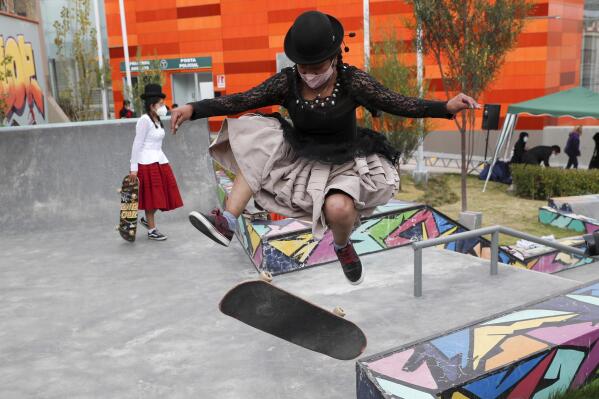 Aide Choque, wearing a mask amid the COVID-19 pandemic, jumps with her skateboard during a youth talent show in La Paz, Bolivia, Wednesday, Sept. 30, 2020. Young women called "Skates Imillas," using the Aymara word for girl Imilla, use traditional Indigenous clothing as a statement of pride of their Indigenous culture when riding their skateboards. (AP Photo/Juan Karita)