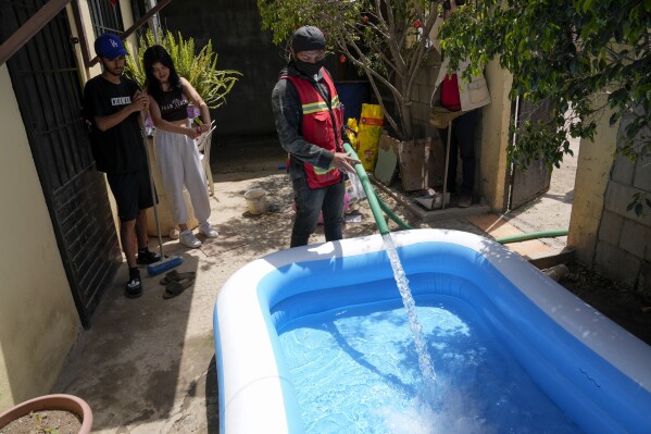 Jose Manuel Perez Reyes, right, fills an inflatable pool at a home Tuesday, May 9, 2023, in Tijuana, Mexico. Among the last cities downstream to receive water from the shrinking Colorado River, Tijuana is staring down a water crisis. (AP Photo/Gregory Bull)