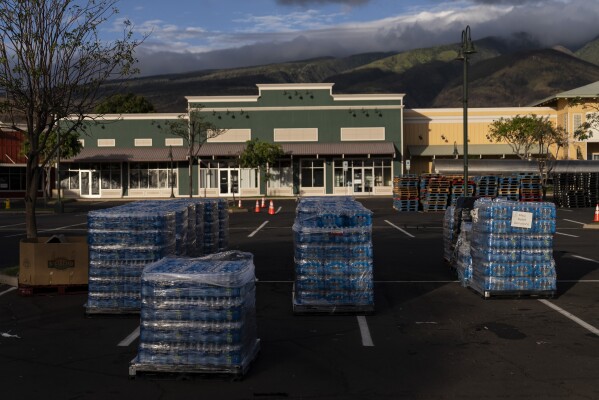 Bottled water is stacked at a food and supply distribution center in Lahaina, Hawaii, Tuesday, Aug. 22, 2023, following a devastating wildfire. Residents of Maui are eager to learn when they can expect safe drinking water to be restored in the wake of last month’s catastrophic wildfires, but extensive testing is still needed and officials are urging patience. (AP Photo/Jae C. Hong)