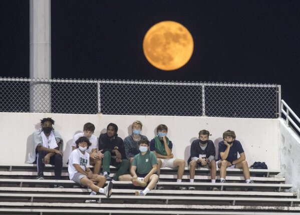 A harvest moon rises with Yenni Stadium in the foreground, while Newman students watch their school play East Jefferson in a high school football game in Metairie, La., during the coronavirus pandemic, Thursday, Oct. 1, 2020. (Chris Granger/The Times-Picayune/The New Orleans Advocate via AP)