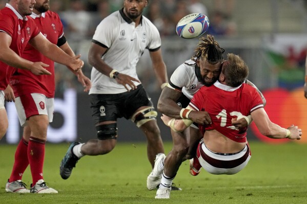 Wales' Nick Tompkins, below, is tackled by Fiji's Waisea Nayacalevu during the Rugby World Cup Pool C match between Wales and Fiji at the Stade de Bordeaux in Bordeaux, France, Sunday, Sept. 10, 2023. (AP Photo/Themba Hadebe)
