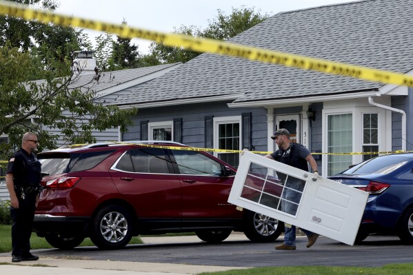 A Romeoville Police officer carries out a door from inside of the home where four people were shot to death, on Monday, Sept. 18, 2023, in Romeoville Ill. (Stacey Wescott/Chicago Tribune via AP)