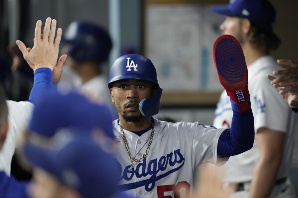 Los Angeles Dodgers' Mookie Betts celebrates in the dugout after scoring off of a double hit by designated hitter J.D. Martinez during the third inning of a baseball game against the San Francisco Giants in Los Angeles, Saturday, Sept. 23, 2023. Max Muncy also scored. (AP Photo/Ashley Landis)