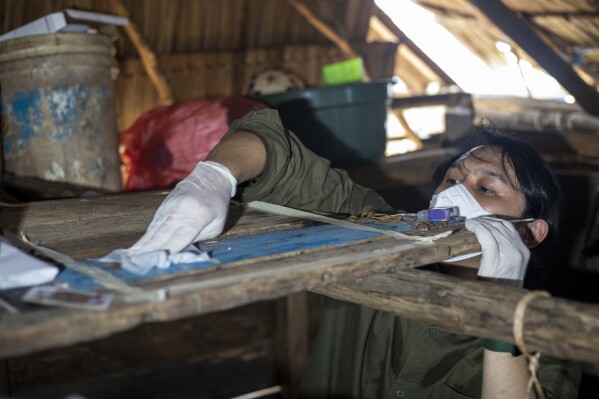 Dhany Alfalah, a researcher for Satya Bumi, a nonprofit environmental organization, collects dust samples from a house on Kabaena Island, Indonesia, Friday, Nov. 15, 2024. (AP Photo/Yusuf Wahil)