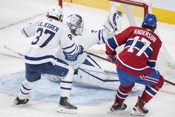 Toronto Maple Leafs goaltender Petr Mrazek, center, makes a save against Montreal Canadiens' Josh Anderson, right, as Maple Leafs' Timothy Liljegren, left, defends during second-period NHL hockey game action in Montreal, Monday, Feb. 21, 2022. (Graham Hughes/The Canadian Press via AP)