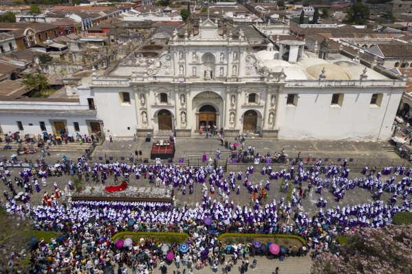Penitents knows as cucuruchos carry a religious float transporting a statue of Jesus Christ bearing a cross, during a Holy Week procession in front of the San Jose Cathedral, in Antigua, Guatemala, on Good Friday, March 29, 2024. (AP Photo/Moises Castillo)