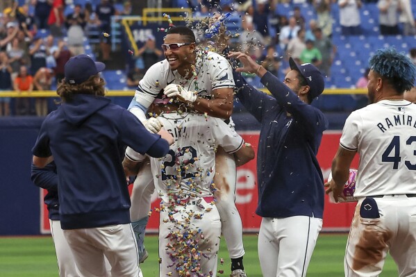 Tampa Bay Rays' Richie Palacios, center, is lifted by Jose Siri after Palacios hit the game-winning RBI single in the 12th inning of a baseball game against the Oakland Athletics, Thursday, May 30, 2024, in St. Petersburg, Fla. The Rays won 6-5 in 12 innings. (AP Photo/Mike Carlson)