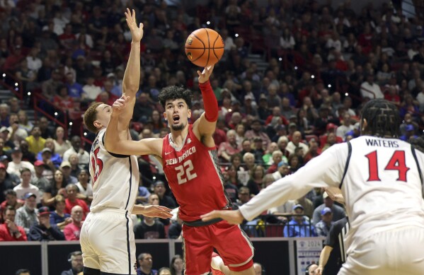 New Mexico forward Mustapha Amzil (22) shoots between San Diego State forward Elijah Saunders (25) and guard Reese Waters (14) during the first half of an NCAA college basketball championship game at the Mountain West Conference tournament Saturday, March 16, 2024, in Las Vegas. (AP Photo/Steve Marcus)