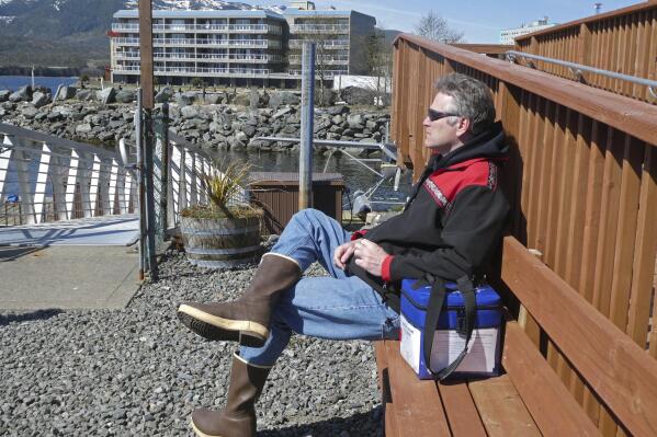 Alaska Gov. Mike Dunleavy sits beside a case containing COVID-19 vaccine doses as he waits near a floatplane dock on Thursday, April 22, 2021, in Ketchikan, Alaska. State health officials have said Alaska has an ample supply of COVID-19 vaccines, and Dunleavy, who flew from Ketchikan to Hyder, Alaska, said he wanted to offer vaccines not only to residents of Hyder but also to Canadians across the border from Hyder in Stewart, British Columbia. (AP Photo/Becky Bohrer)