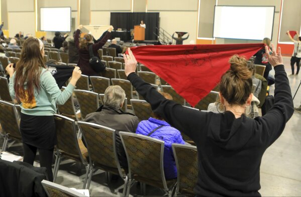 FILE - In this Feb. 11, 2019 file photo, protesters hold up flags during a public hearing on a draft environmental plan on proposed petroleum leasing within Alaska's Arctic National Wildlife Refuge in Anchorage, Alaska. Conservationists will try to persuade a U.S. judge to stop the Trump administration from issuing leases to oil and gas companies in the Arctic National Wildlife Refuge. The Anchorage Daily News reported that the videoconference Monday, Jan. 4, 2021, in U.S. District Court in Anchorage is expected to determine whether the Bureau of Land Management can open bids in an online lease sale scheduled for Wednesday. The agency has offered 10-year leases on 22 tracts covering about 1,563 square miles in the coastal plain, which accounts for about 5% of the refuge's area. (AP Photo/Dan Joling, File)