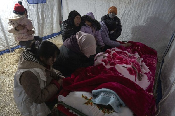 Family members grieve over the body of Han Suofeiya who was killed in an earthquake in Yangwa village near Dahejia town in northwestern China's Gansu province, Wednesday, Dec. 20, 2023. (AP Photo/Ng Han Guan)