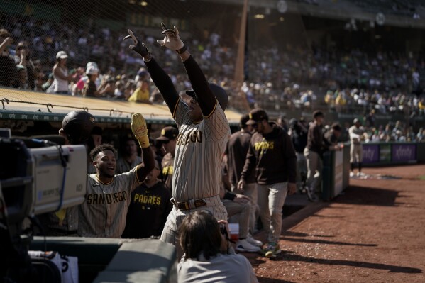 San Diego Padres' Juan Soto, center, gestures to the crowd from the dugout after hitting a grand slam against the Oakland Athletics during the eighth inning of a baseball game, Sunday, Sept. 17, 2023, in Oakland, Calif. (AP Photo/Godofredo A. Vásquez)