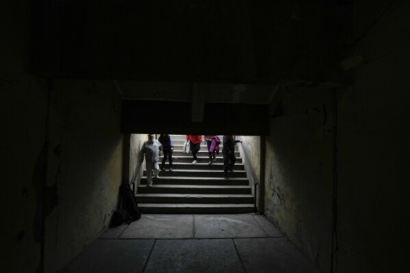 Jaime Zorondo, left, accompanied by relatives, descends the stairs that leads to a tunnel at the National Stadium once used as a prison and place of torture, where he was detained on Sept. 1973, in Santiago, Chile, Saturday, Sept. 2, 2023. Zorondo is taking part in a meeting of former detainees as part of the 50th commemoration of the military coup led by Gen. Augusto Pinochet that overthrew Chile's late President Salvador Allende. (AP Photo/Esteban Felix)