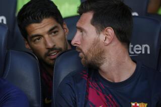 FILE - In this Sunday, Aug. 4, 2019 file photo, Barcelona's Lionel Messi, right, talks with teammate Luis Suarez on the bench before the Joan Gamper trophy soccer match against Arsenal at the Camp Nou stadium in Barcelona, Spain. Luis Suarez and Lionel Messi spent years hanging out at their neighboring homes on the Mediterranean coast when taking a break from scoring goals for Barcelona. On Saturday, May 8, 2021 Suarez will return to Camp Nou aiming to knock his former team out of the Spanish league title race.(AP Photo/Joan Monfort, file)