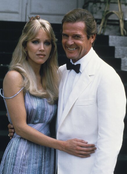 FILE - Actor Roger Moore, right, poses with his co-star Tanya Roberts from the James Bond film "A View to a Kill," outside of Château de Chantilly in Chantilly, France on Aug. 17, 1984. Roberts, who captivated James Bond in “A View to a Kill” and appeared in the sitcom “That ’70s Show,” died Monday,  Jan. 4, 2021, several hours after she was mistakenly declared dead by her publicist and her partner. Roberts' partner Lance O'Brien confirmed her death Tuesday after picking up her personal effects at a Los Angeles hospital. She was 65. (AP Photo/Alexis Duclos, File)