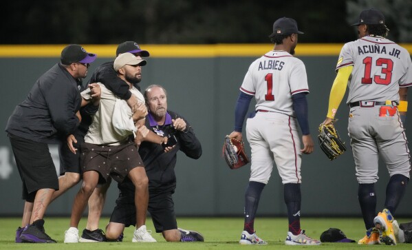 Fans run onto field and one makes contact with Atlanta Braves star