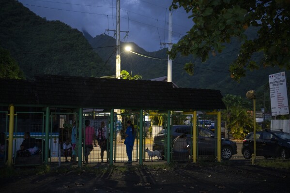 Locals hang out at a bus stop at the end of the road in Teahupo'o, Tahiti, French Polynesia, Wednesday, Jan. 17, 2024. (AP Photo/Daniel Cole)