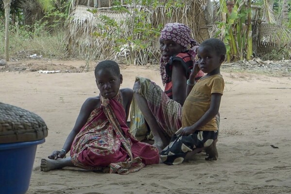 FILE - In this image made from video, a woman with children watch as Rwandan soldiers patrol in the village of Mute, in Cabo Delgado province, Mozambique Monday, Aug. 9, 2021. A surge of new attacks by an Islamic State-affiliated group in Mozambique's Cabo Delgado province has left more than 70 children missing, with fears they may have drowned in a river or been kidnapped by militants as thousands of families fled the violence, local authorities and a group of aid agencies said. (AP Photo/Marc Hoogsteyns, File)