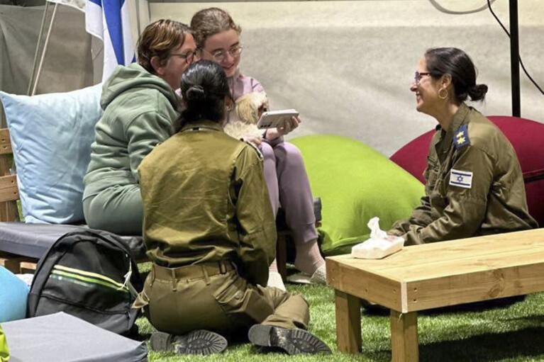 Esta fotografía proporcionada por GPO muestra a Gabriela y Mia Leimberg, atrás, hablando con su familia desde un punto de encuentro en territorio israelí después de ser liberadas por Hamas, el martes 28 de noviembre de 2023. (GPO/Handout vía AP)