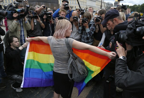 FILE - A gay rights activist stands with a rainbow flag during a protest in Palace Square in St. Petersburg, Russia, on Aug. 2, 2015. Russian authorities have adopted a slew of laws restricting fundamental human rights, including freedom of speech and assembly, as well as the rights of minorities and religious groups. (AP Photo, File)