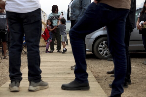 Brittani Tomma holds her children Aiyanna Scarff, 5, and her brother Talon Tomma-Scarff as Premier David Eby meets with Chief James Tomma from the Little Shushwap Lake as they tour the Tselletkwe Lodge, an evacuation location amid wildfires, in Kamloops, British Columbia, Tuesday, Aug. 22, 2023. (Chad Hipolito/The Canadian Press via AP)