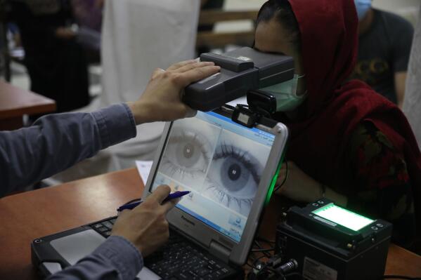 FILE - In this June 30, 2021, file photo an employee scans the eyes of a woman for biometric data needed to apply for a passport, at the passport office in Kabul, Afghanistan. Over two decades, the United States and its allies spent hundreds of millions of dollars building databases for the Afghan people. The nobly stated goal was to promote law and order and government accountability, and to modernize a war-ravaged land.  But in the Taliban’s lightning seizure of power, most of that digital apparatus fell into the hands of an unreliable rulers. Built with few data-protection safeguards, it risks becoming the high-tech jackboots of a surveillance state. (AP Photo/Rahmat Gul, File)