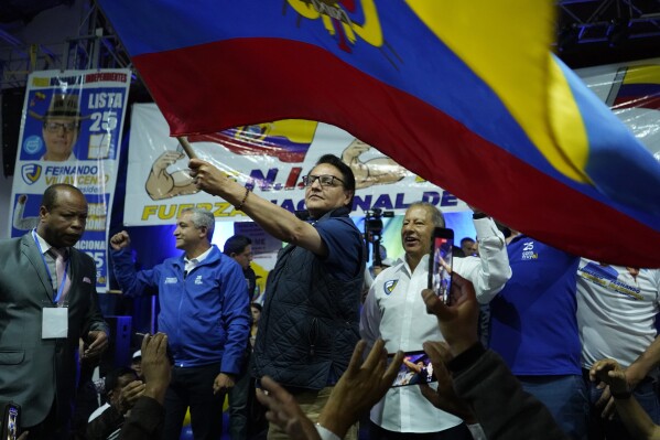 FILE - Presidential candidate Fernando Villavicencio waves a national flag during a campaign event at a school minutes before he was shot to death outside the same school, in Quito, Ecuador, Aug. 9, 2023. The Attorney General's Office asked on Tuesday, Feb. 27, 2024, to call to trial six suspects involved in the murder of presidential candidate Villavicencio in August of last year and argued that his death was planned from a maximum security prison cell by an organization linked to the criminal group Los Lobos. (API via AP File)