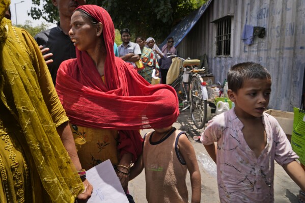 A woman covers a child with her scarf to protect him from the sun as a heat wave grips the Indian capital New Delhi, India, Thursday, May 30, 2024. Officials say a scorching heat wave has killed at least 14 people, including 10 election officials, in eastern India with temperatures soaring up to 49.9 degrees Celsius (122 degrees Fahrenheit) in parts of India this week. (AP Photo/Manish Swarup)