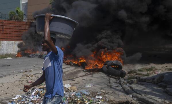 Burning tires block a road, set by protesters in Port-au-Prince, Haiti, Monday, Oct. 18, 2021. Workers angry about the nation’s lack of security went on strike in protest two days after 17 members of a U.S.-based missionary group were abducted by a violent gang. (AP Photo/Joseph Odelyn)