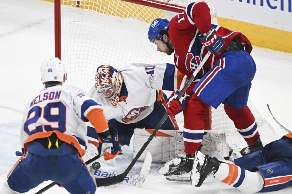 New York Islanders goaltender Semyon Varlamov is scored on by Montreal Canadiens' Josh Anderson (17) as Islanders' Brock Nelson (29) defends during the second period of an NHL hockey match in Montreal, Saturday, Dec. 16, 2023. (Graham Hughes/The Canadian Press via AP)