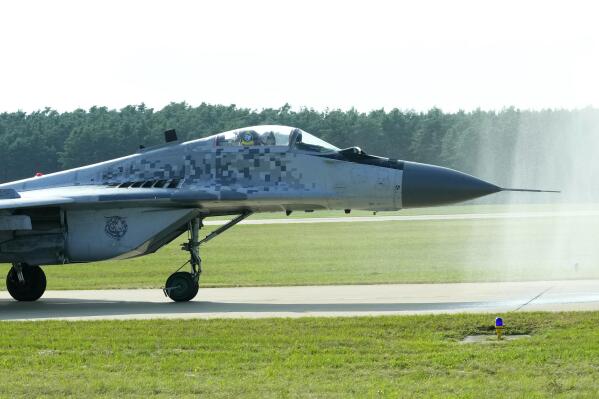 FILE - Slovak Air Force MiG-29 goes through a water gate during an airshow in Malacky, Slovakia, Saturday, Aug. 27, 2022. On Friday March 17, 2023 Slovakia's government has approved a plan to give Ukraine its fleet of 13 Soviet-era MiG-29 fighter jets, becoming the second NATO member country to agree to fulfill the Ukrainian government's pleas for warplanes to help defend against Russia's invasion. (AP Photo/Petr David Josek,File)
