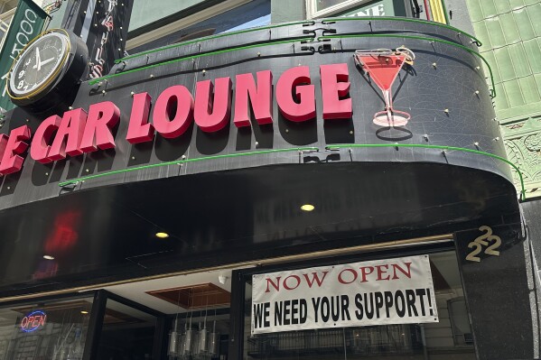 A banner asking for support hangs outside the Sam's Cable Car Lounge near Union Square in San Francisco, on June 21, 2023. San Francisco's downtown has seen an exodus of retailers. While San Francisco faces some of its own unique issues the problems serve as warning signs for other downtowns across the country, which are also feeling some pain. (AP Photo/Eric Risberg)