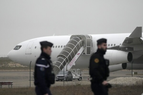 Gendarmes patrol by the plane grounded by police based that it could be carrying trafficking victims, at the Vary airport , Monday, Dec. 25, 2023 in Vatry, eastern France. (AP Photo/Christophe Ena)