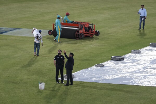 Umpires Aleem Dar, center in black kit, with Ahsan Raza examine condition as ground staff start work to ready ground after rain delay the start of first T20 cricket match between Pakistan and New Zealand, in Rawalpindi, Pakistan, Thursday, April 18, 2024. (AP Photo/Anjum Naveed)