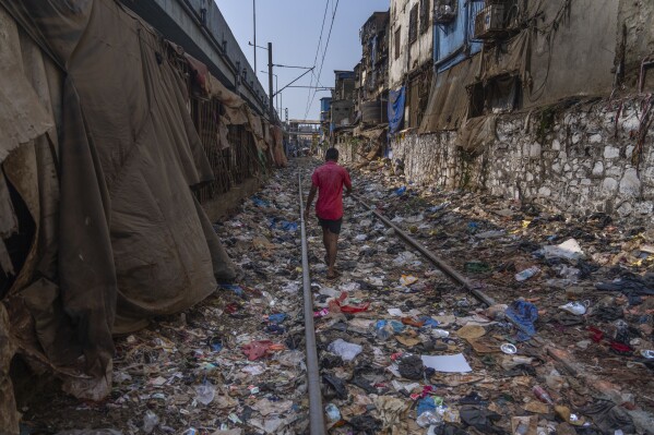 FILE - A man walks on a railway track littered with plastic and other waste materials on Earth Day in Mumbai, India, April 22, 2024. (AP Photo/Rafiq Maqbool, File)