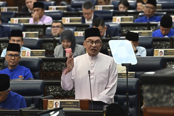 In this photo released by Malaysia's Department of Information, Malaysia's Prime Minister and Finance Minister Anwar Ibrahim delivers his 2024 budget speech at the Parliament in Kuala Lumpur, Malaysia, Friday, Oct. 13, 2023. (Malaysia's Department of Information via AP)