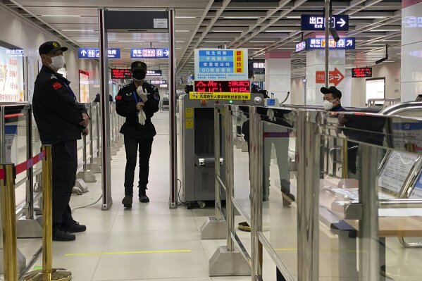 In this April 1, 2020, photo, security personnel work a check point in Wuhan in central China's Hubei province. Life in China post-coronavirus outbreak is ruled by a green symbol on a smartphone screen. Green signifies the "health code" that says the user is symptom-free. It is required to board a subway, check into a hotel or enter Wuhan, the city where the global pandemic began. (AP Photo/Ng Han Guan)