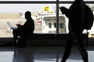 FILE - In this Wednesday, Nov. 21, 2018 file photo, travelers check their phones at Indianapolis International Airport in Indianapolis. On Tuesday, Nov. 12, 2019, a federal court in Boston ruled that warrantless U.S. government searches of the phones and laptops of international travelers at airports and other U.S. ports of entry violate the Fourth Amendment. (AP Photo/Michael Conroy)