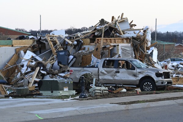 A damaged car sits by homes destroyed in the West Creek Farms neighborhood on Sunday, Dec. 10, 2023, Clarksville, Tenn. Central Tennessee residents and emergency workers are continuing the cleanup from severe weekend storms. (AP Photo/Mark Zaleski)